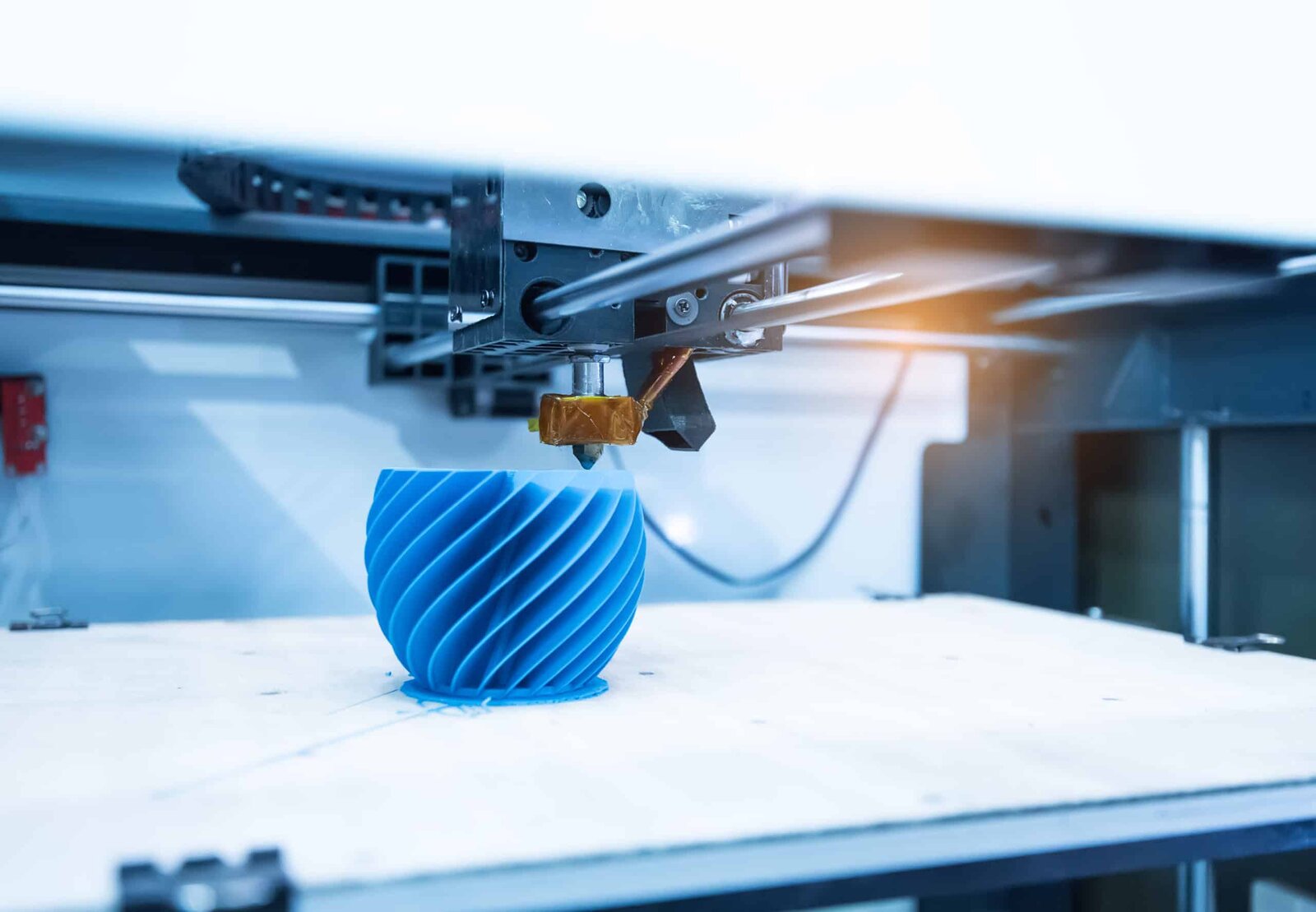 FDM 3D printer building a blue part on the print bed